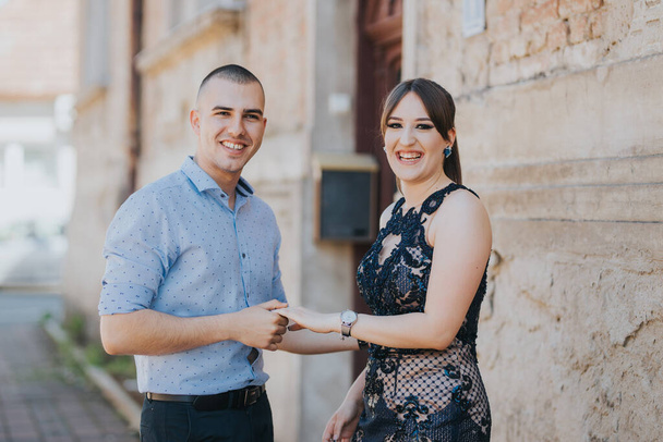 A beautiful elegantly dressed happy couple near a brick wall outdoor - Foto, afbeelding