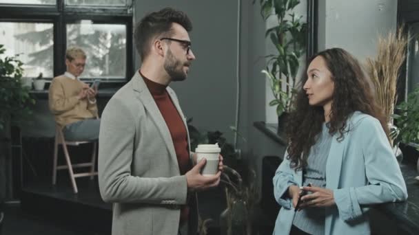 Medium slowmo portret van twee jonge collega 's poseren voor de camera staan in moderne coworking office hebben gesprek - Video