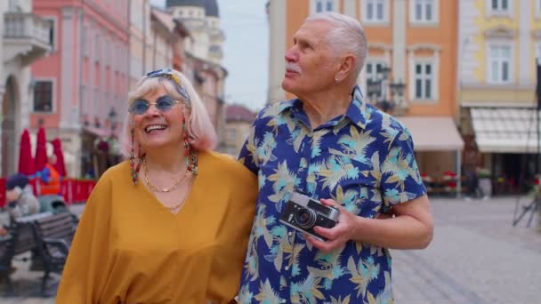 Старшие старые стильные туристы мужчина, женщина, бабушка, дед семьи, имеющие прогулку в летнем городе - Кадры, видео