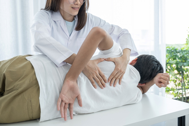 Mãos femininas fazendo fisioterapia Estendendo as costas de um paciente do sexo masculino. - Foto, Imagem