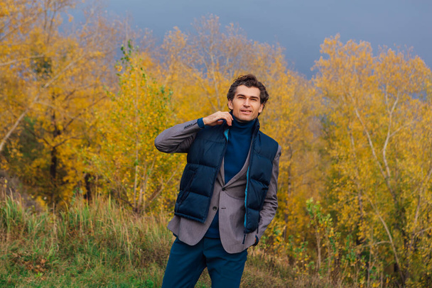 Tall handsome man walking outdoor in yellow autumn forest on the hill before storm - Foto, Bild
