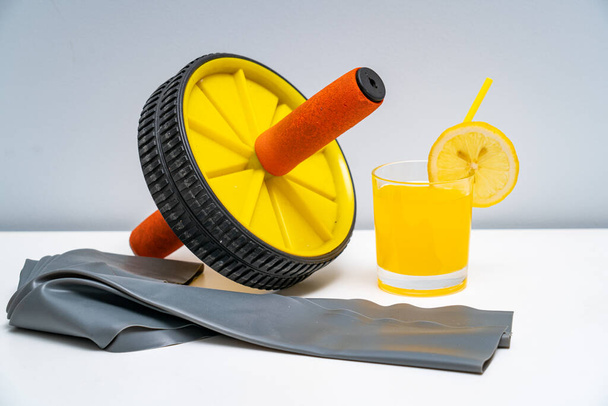 Una rueda del abdomen y un vaso de jugo en la mesa blanca - Foto, Imagen