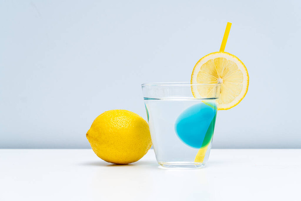 Un vaso de limonada y un limón fresco en la mesa blanca - Foto, Imagen