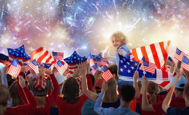 Amerikaanse familie viert 4 juli. Mensen kijken naar Independence Day vuurwerk met Amerikaanse vlag. Trots USA menigte juichen en vieren. Groep met Amerika symbool. Nationaal feestfeest. - Foto, afbeelding