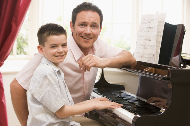 Man and young boy playing piano and smiling - Foto, Bild