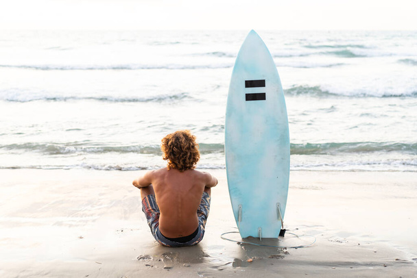 Joven caucásico hombre levantarse temprano a hacer surf al amanecer - Foto, Imagen