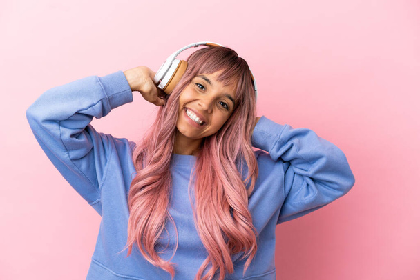 Fiatal vegyes verseny nő rózsaszín haj elszigetelt rózsaszín háttér hallgat zenét - Fotó, kép