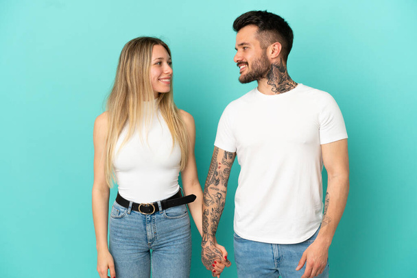 Jovem casal sobre isolado fundo azul de mãos dadas - Foto, Imagem
