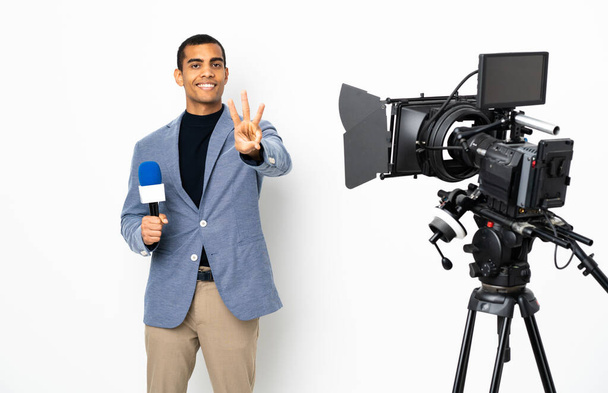 Reporter Afroamerykanin trzyma mikrofon i raportuje wiadomości na odizolowanym białym tle szczęśliwy i liczy trzech z palcami - Zdjęcie, obraz