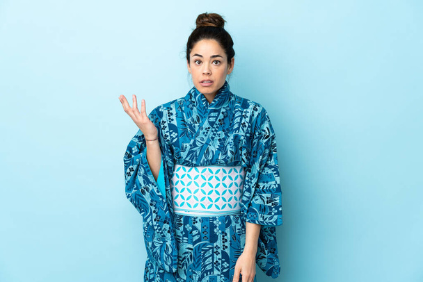 Woman wearing kimono over isolated background making doubts gesture - Fotó, kép