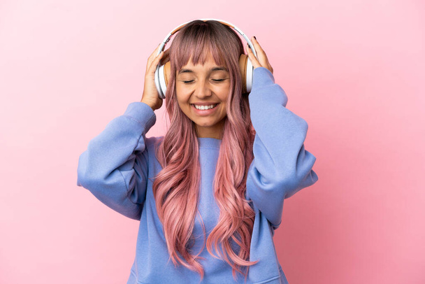Young mixed race woman with pink hair isolated on pink background listening music - Fotografie, Obrázek