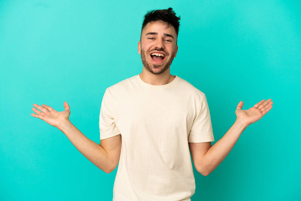 Young caucasian man isolated on blue background with shocked facial expression - Photo, Image