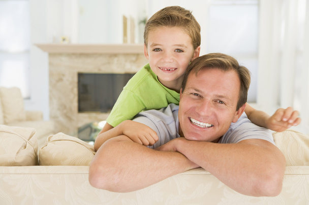 Man and young boy sitting in living room smiling - Photo, image