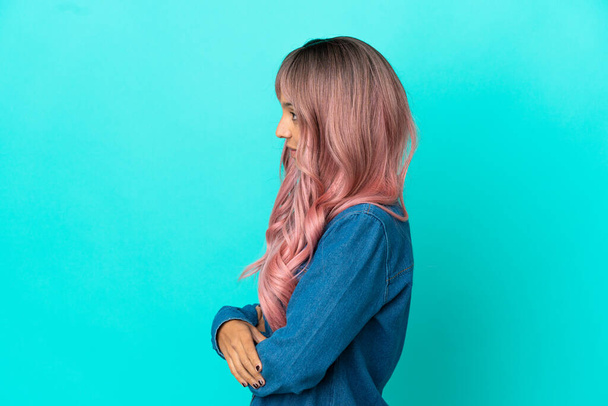 Mladá smíšená závod žena s růžovými vlasy izolované na modrém pozadí v boční poloze - Fotografie, Obrázek