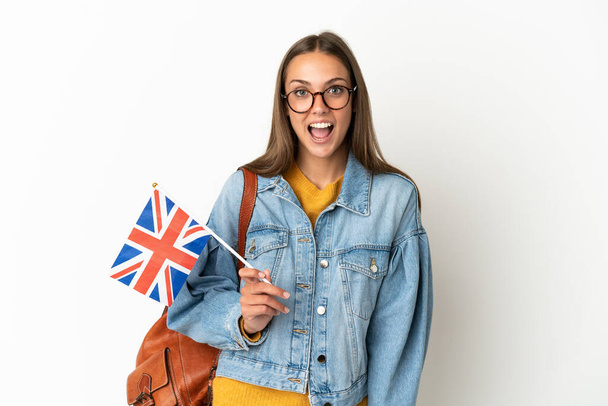 Junge hispanische Frau mit einer britischen Flagge auf isoliertem weißem Hintergrund und überraschendem Gesichtsausdruck - Foto, Bild