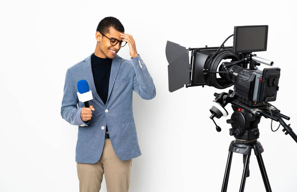 Репортер афроамериканец держит микрофон и сообщает новости на изолированном белом фоне смеясь - Фото, изображение