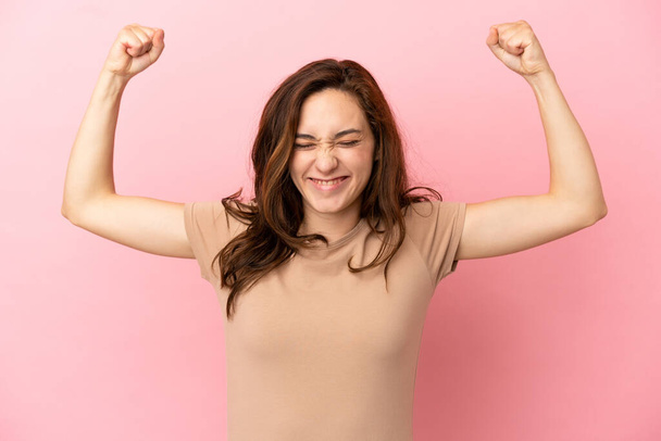 Young caucasian woman isolated on pink background doing strong gesture - Photo, Image