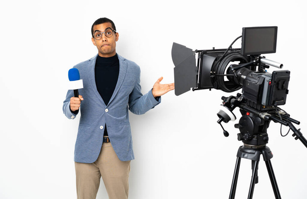 Muhabir Afrikalı Amerikalı bir adam mikrofon tutuyor ve beyaz arka planda şüpheli hareketler yapıyor. - Fotoğraf, Görsel