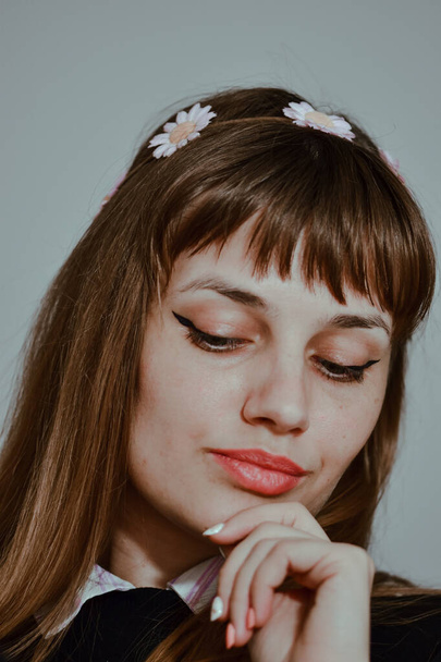 A vertical portrait of a caucasian female with a daisy hairband looking down and thinking - Foto, Bild