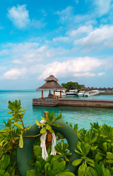 Paisaje panorámico de la playa de Maldivas y muelle con lanchas rápidas y yates en el horizonte. Paisaje marino con bungalows de agua, hermoso mar turquesa y aguas de laguna, paraíso de la naturaleza tropical.  - Foto, imagen