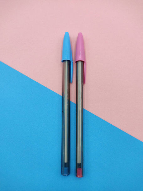 An overhead shot of two color pens on blue and pink paper background - Foto, Imagen