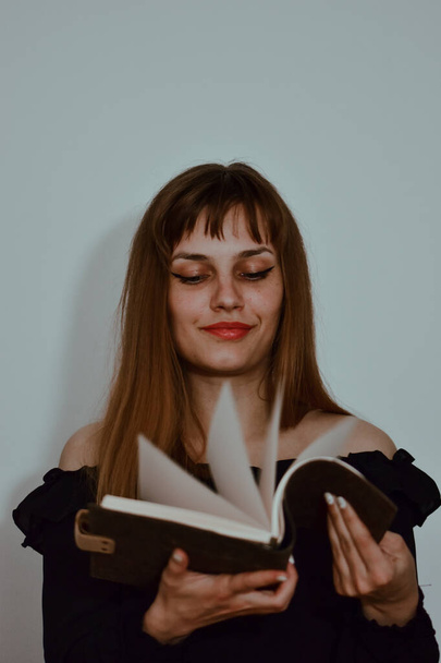 A portrait of a smiling caucasian female looking through a notebook isolated on a white background - Fotografie, Obrázek