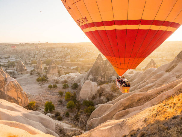 A hot air balloon flying over rocky mountains at scenic sunrise in Cappadocia, Turkey - Foto, Bild