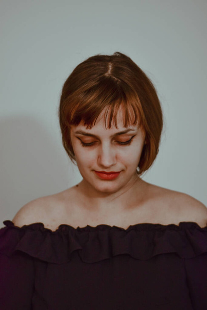 Een verticaal portret van een jonge blanke vrouw naar beneden kijkend geïsoleerd op een witte achtergrond - Foto, afbeelding