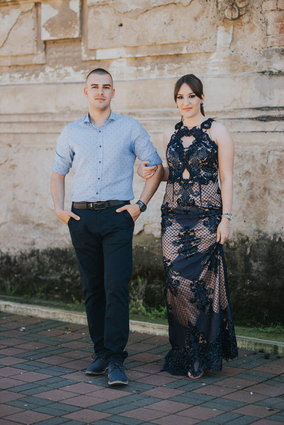 A beautiful elegantly dressed couple posing near a brick wall outdoor - Fotografie, Obrázek