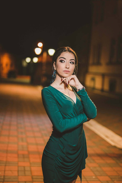 A shallow focus of an adult woman wearing an elegant green dress outdoors at night - Foto, Imagen