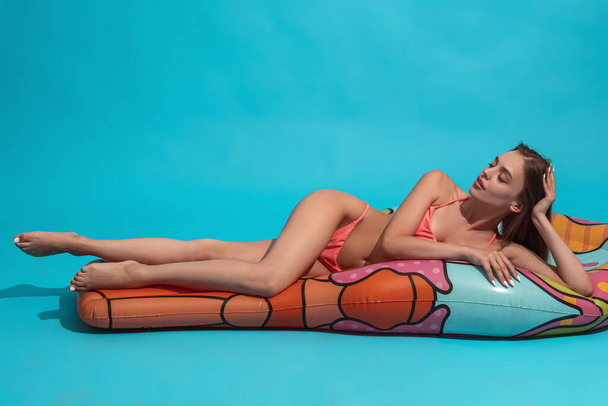 Розслаблена жінка в бікіні, що лежить із закритими очима на надувному матраці
 - Фото, зображення