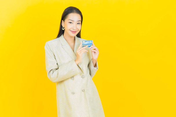 Портрет красива молода азіатка посміхається з кредитною карткою на кольоровому фоні
 - Фото, зображення