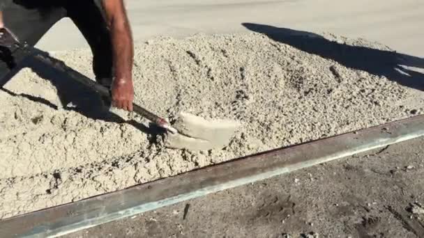 Costruttori irriconoscibili che lavorano insieme per livellare il cemento tra vialetto e strada. - Filmati, video