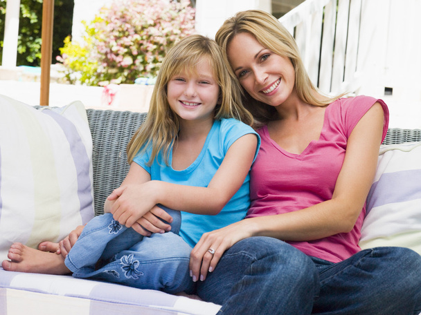 Woman and young girl sitting on patio smiling - Photo, image
