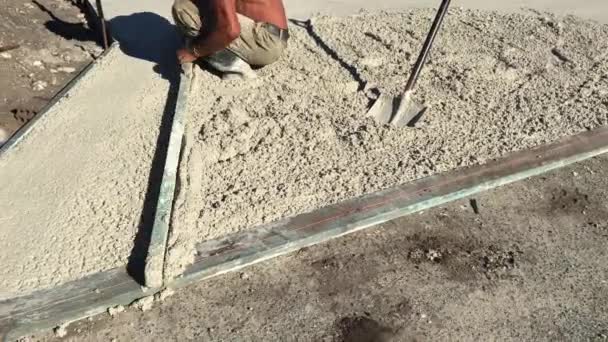 Garaj yolu ve sokak yolu arasındaki çimentoyu dengelemek için çalışan tanınmamış bir inşaatçı. - Video, Çekim