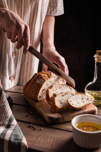 Woman cuts freshly baked bread - Foto, imagen