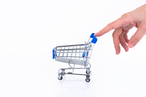 Female hand with fingers pushing a shopping cart isolated on white background. Copy space. - 写真・画像