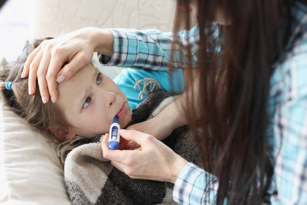 Matka mierzy temperaturę małej dziewczynki z termometrem w ustach - Zdjęcie, obraz