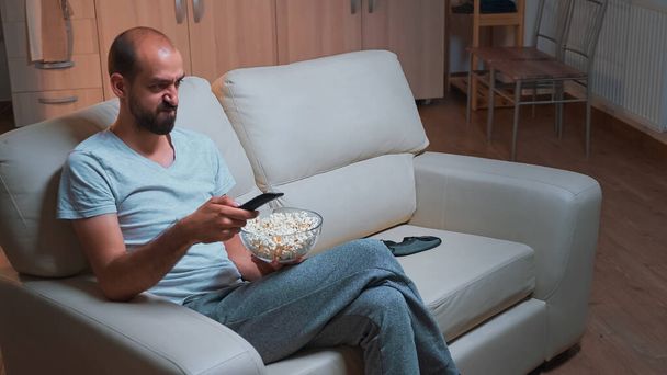 Homem concentrado sentado na frente da televisão usando controle remoto - Foto, Imagem