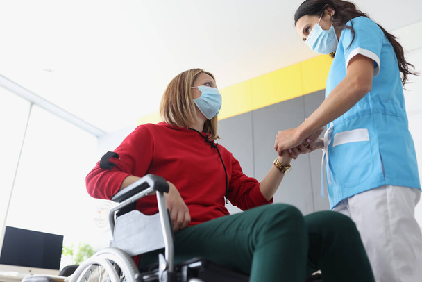 Lékař fyzioterapeut v ochranné lékařské masce pracuje ruku zdravotně postiženého pacienta na klinice - Fotografie, Obrázek
