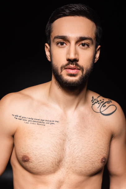 Shirtless tattooed man looking at camera isolated on black  - Photo, Image