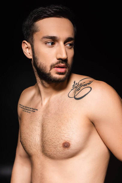 Tattooed man with shirtless torso looking away isolated on black  - Φωτογραφία, εικόνα
