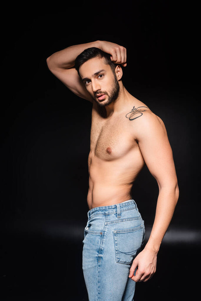 Shirtless man in jeans posing on black background  - Foto, immagini