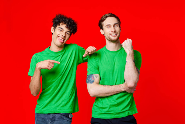 Dos amigos alegres con camisetas verdes están parados uno al lado del otro - Foto, Imagen