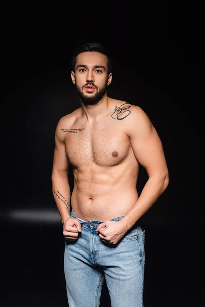 Shirtless tattooed man looking at camera on black background  - Fotografie, Obrázek