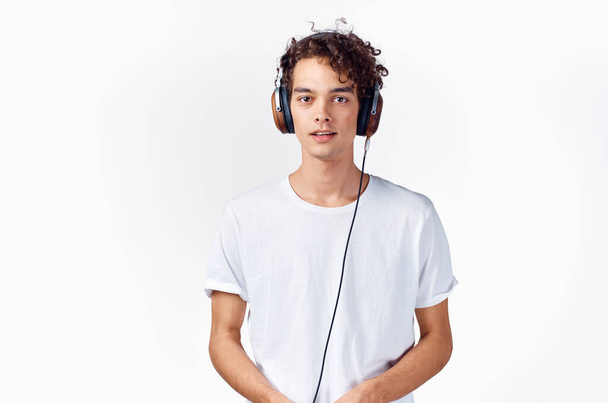 Ένας άντρας με λευκό μπλουζάκι με ακουστικά ακούει μουσική.  - Φωτογραφία, εικόνα