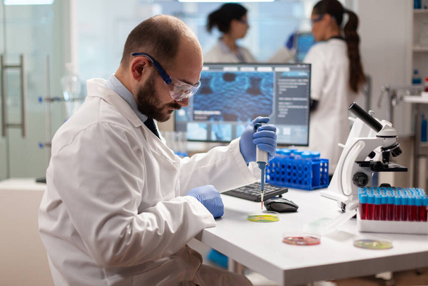 Фармацевтический ученый сбрасывает образец крови с помощью микропипетки - Фото, изображение