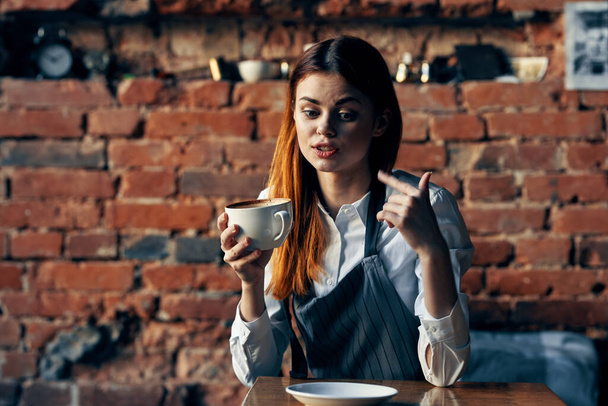 camarera con taza de café sentada a la mesa  - Foto, imagen