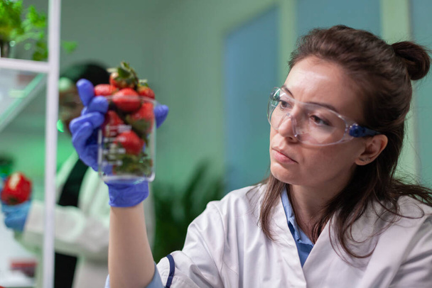 農薬を注入されたイチゴのグラスを持つ研究者 - 写真・画像