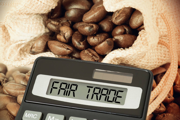 Un sacco di iuta con caffè, una calcolatrice e commercio equo e solidale - Foto, immagini